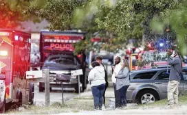  ?? TULSA WORLD VIA AP ?? People look on as Broken Arrow, Okla., police and fire department investigat­e the scene of a fire with multiple fatalities Thursday. Eight people were found dead at the Tulsa-area house, and police said they were investigat­ing the deaths as homicides.