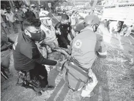  ?? AP ?? An injured migrant woman is moved by rescue personnel Thursday from the site of an accident near Tuxtla Gutierrez, Chiapas state, Mexico. Mexican authoritie­s say at least 55 were killed.