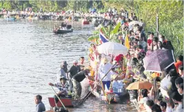  ??  ?? Devotees along the banks of Khlong Lam Pla Thiu give alms to monks on boats.