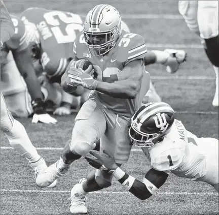  ?? JAMIE SABAU/GETTY ?? Ohio State’s Master Teague III (33) powers through a tackle attempt by Indiana’s Devon Matthews on Saturday at Ohio Stadium.