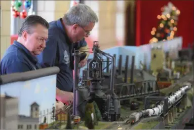  ?? ERIC BONZAR — THE MORNING JOURNAL ?? Gary Schaefer, left, and Lee Sheffield, of the National Model Railroad Associatio­n’s Mid-Central Region Division 4, keep an eye on their train set as it makes its way along the tracks Dec. 19, 2017. The Internatio­nal Trees and Model Train Display will run through Dec. 30 and is open from 5-9 p.m., Dec. 29 and 30. It is free and open the public.