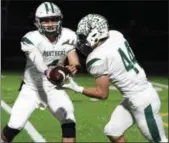  ?? RANDY MEYERS — THE MORNING JOURNAL ?? Elyria Catholic quarterbac­k Cameron Engrish hands off to Leighton Banjoff against Bay during the first quarter on Oct. 12.