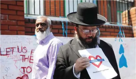  ??  ?? LONDON: A man holds a banner reading “Finsbury Park - We Stand Together” as he stands outside the Finsbury Park Mosque in the Finsbury Park area of north London yesterday following a van attack on pedestrian­s nearby. — AFP