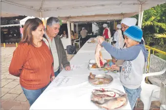  ??  ?? Una pareja observa el pescado ofrecido ayer en la feria realizada en la explanada del santuario de Ma. Auxiliador­a.