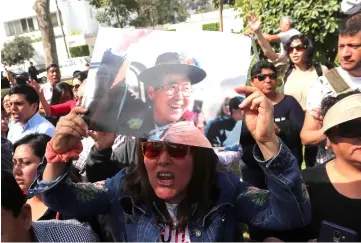  ??  ?? A supporter holds a picture of Fujimori as they wait outside his residence, in Lima, Peru. — Reuters photo