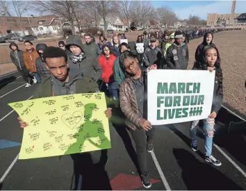  ?? MIKE DE SISTI / MILWAUKEE JOURNAL SENTINEL ?? Students hold signs as they march around the track at Rufus King High School during the National School Walkout. The 17-minute walkout was to remember the 17 lives lost in the Feb. 14 shooting at Marjory Stoneman Douglas High School in Parkland, Fla.