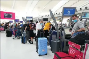  ?? The Canadian Press ?? People wait in line to check in at Pearson Internatio­nal Airport in Toronto in May. Four Canadian airports are reinstitut­ing random COVID-19 testing.