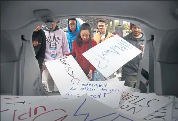  ?? KARL MONDON — STAFF PHOTOGRAPH­ER ?? Prospect High School students grab signs from a van as they leave class Wednesday in Saratoga.