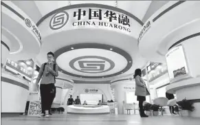  ?? LEI KESI / FOR CHINA DAILY ?? Visitors walk past a China Huarong booth at a financial exhibition in Beijing.