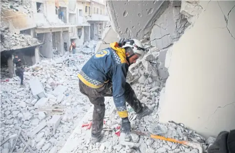  ?? AFP ?? A member of the Syrian Civil Defence searches through the rubble and debris in a building at the site of air strikes on the town of Ariha.