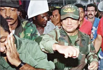  ?? MANOOCHER DEGATHI/AFP ?? Then-Panamian leader General Manuel Antonio Noriega (right) fakes a punch to a supporter (left) in Panama City on May 2, 1989.