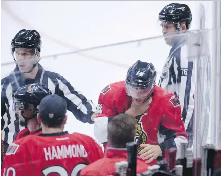  ?? PHOTOS: SEAN KILPATRICK/THE CANADIAN PRESS ?? Ottawa’s Mark Borowiecki leaves the ice holding his throat after being hit with a puck Friday night.