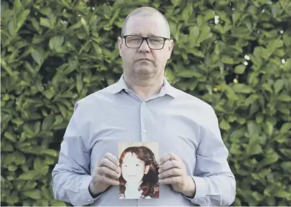  ??  ?? Mark Kelly holds a photograph of his sister Carol-ann, who died after being struck by a plastic bullet in 1981