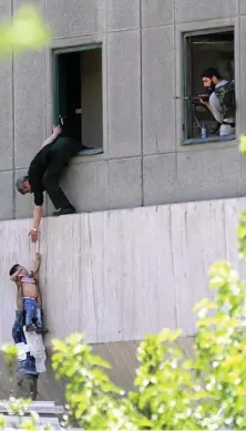  ?? PHOTO: OMID WAHABZADEH ?? DESPERATE MEASURES: Iranian policemen try to help civilians fleeing the Parliament.