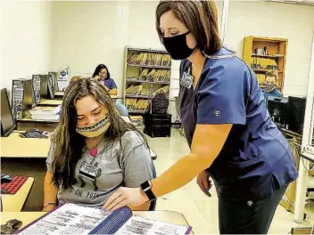  ?? BIANCA MOORMAN AP ?? Rebecca Higginboth­am of the Health Informatio­n Technology program at Meridian Community College in Meridian, Miss., helps a student. Mississipp­i is among the states using relief aid to pay for job training.