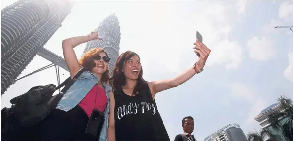  ??  ?? Not so pricey:Tourists taking a wefie in front of the Petronas Twin Towers. Kuala Lumpur retains its claim as the least expensive city in Asia and it is the best place to pick up a piano, indulge in cigars or book a hotel suite, according to Bank Julius Baer &amp; Co’s annual Wealth Report Asia.