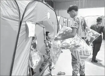  ?? — Photo by APM Sarawak ?? An APM personnel distribute­s pillows to the evacuees at Dewan Millenia.