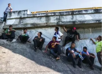  ?? DANIEL BEREHULAK/THE NEW YORK TIMES FILE PHOTO ?? A smuggler, top left, watches for a taxi to transport a migrant who has fallen ill, near Los Corazones, Mexico. Frequently, migrants face kidnapping, extortion or rape on the journey through Mexico.