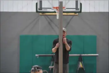  ?? ERIC BONZAR — THE MORNING JOURNAL ?? John Todd, owner and contractor for Cleveland-based Tec Athletics, levels out a volleyball net post at center court of Avon Lake Parks and Recreation Department’s Anchor Recreation­al Facility in the Artstown Plaza on Feb. 7. The new indoor space, 33483...