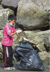  ?? — afp ?? a young volunteer collecting trash in a coastal area as part of World Cleanup day in banda aceh, Indonesia, recently.