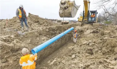  ?? MIKE HENSEN FILES ?? Constructi­on workers lower a section of pipe that will be used for a water line into a trench. This is an opportunit­y for government­s to implement strategies that go beyond the current crisis, writes Jerry Dias, and use bold ideas to stabilize the economy in preparatio­n of meeting future crises, such as climate-related events.