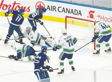  ?? NICK TURCHIARO / USA TODAY SPORTS ?? Leafs centre William Nylander battles for a puck in front of Vancouver Canucks goaltender Braden Holtby during the second period at Scotiabank Arena on Monday,
the third straight meeting between the North Division rivals.