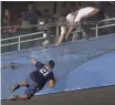  ?? BILL KOSTROUN, AP ?? Security guards reach for a fan who fell onto the net behind home plate at Yankee Stadium in 2000.