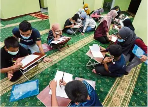  ??  ?? Giving back to society: A group of young profession­als, led by its co-ordinator Khairul (second left), guiding children at Surau Al-Muhajirin of Flat PPR Jalan Sungai in George Town, Penang.