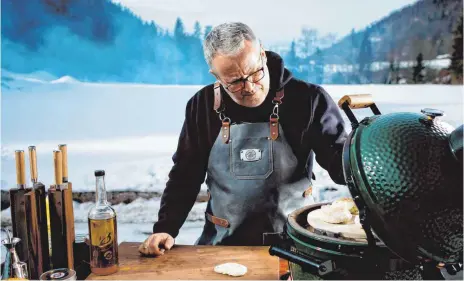  ?? FOTOS: MARKUS GMEINER/DPA ?? Bei Kochbuchau­tor Tom Heinzle bleibt der Grill auch im Winter nicht kalt.