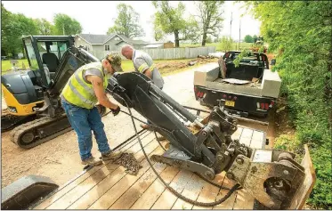  ?? NWA Democrat-Gazette/BEN GOFF • @NWABENGOFF ?? Jack Hutcheson (left) and Shawn Alley with the Benton County Road Department swap a bucket for a compactor attachment on an excavator May 10 while replacing drainage culverts and grading the road surface along Accident Road near Springdale.