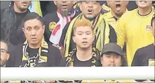  ?? ?? Derrick (centre), nicknamed ‘brown haired bro’ by netizens, is seen among the malaysian fans at the al Janoub Stadium. — aFP photo