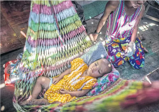  ??  ?? DROWSY: San Min Hteik, right, babysits his sister at their home in the Myaung Dagar industrial zone in Hmawbi Township in Yangon.