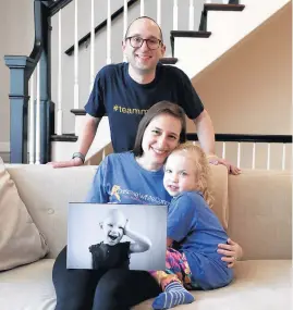  ?? ABEL URIBE/CHICAGO TRIBUNE ?? Scott and Pammy Kramer show a picture of their daughter Maddie while sitting with their younger daughter, Lily, 4, at their Lakeview home.