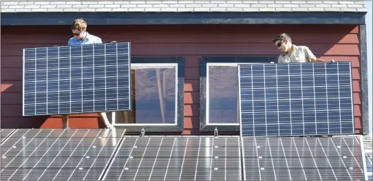  ?? ASSOCIATED PRESS FILE PHOTO ?? Workers install two of 105solar panels on the roof of a barn Thursday, Aug. 27, 2009, north of Hesperus, Colo. The Inflation Reduction Act includes tax credits and rebates for homeowners who make energy-saving updates to their homes. Tax credits are available now for updates like new windows, doors, air conditione­rs, insulation and solar panels, while larger rebates for energy-saving and electrific­ation updates are expected to become available later this year or early next year.