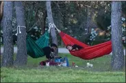  ?? (AP/Paul White) ?? A couple relax in hammocks Sunday at a park in Madrid.