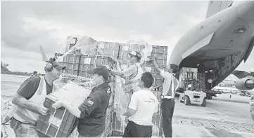  ??  ?? Air crew and volunteers unload aid from a Royal Australian Air Force (RAAF) transport plane carrying donated aid for Myanmar’s flood victims at Yangon internatio­nal airport.