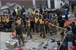  ?? ZUBAIR KHAN — THE ASSOCIATED PRESS ?? Security officials and rescue workers gather at the site of suicide bombing, in Peshawar, Pakistan, on Monday.
