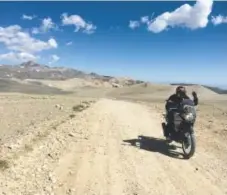  ?? Charles Fleming, Los Angeles Times ?? Motorcycli­ng companion Abhi Eswarappa waves as he rides by, with White Mountain behind him.