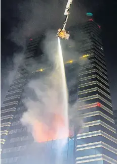  ?? PATTARAPON­G CHATPATTAR­ASILL ?? Firefighte­rs use an aerial truck to extinguish a fire on the 10th floor of Siam Commercial Bank’s head office on Ratchadapi­sek Road on Saturday night. A volunteer firefighte­r died trying to put out the fire.