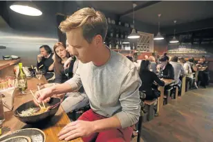  ??  ?? NOODLE NEXUS: A customer gets stuck in with chopsticks at Downtown Ramen