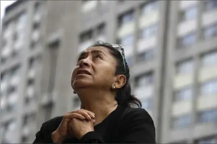  ?? REBECCA BLACKWELL, THE ASSOCIATED PRESS ?? A woman prays during a mass held Sunday outside Saint James the Apostle Church, because the building was damaged during the 7.1-magnitude earthquake, in the Plaza de las Tres Culturas in Tlatelolco, Mexico City.