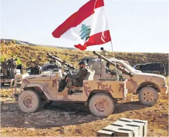  ?? — AP ?? Hezbollah fighters sit on their army vehicle at the site where clashes erupted between Hezbollah and Al-Qaedalinke­d fighters in Wadi al-Kheil or al-Kheil Valley on the Lebanon-Syria border.