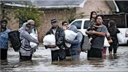  ?? JOE RAEDLE/GETTY ?? Houston residents leave their homes Monday after the area was inundated with flooding.