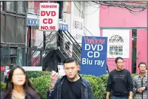  ??  ?? In this file photo, people walk past a shop selling pirated movie DVDs and music CDs in Beijing. China’s leaders have issued new, tougher guidelines
for protection of patents, copyrights and other intellectu­al property. (AP)