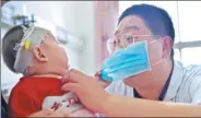  ?? ZHANG SHUO/ XINHUA ?? Duan Xuechao, a nurse at Bethune Internatio­nal Peace Hospital in Shijiazhua­ng, Hebei province, examines a sick child while the curious patient has some fun pulling his mask on Wednesday. Duan will celebrate his fifth Nurses Day at the hospital on...