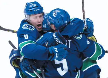  ?? CP PHOTO ?? From left, Brock Boeser, Elias Pettersson and Derrick Pouliot of the Vancouver Canucks celebrate Pouliot’s overtime goal against the Colorado Avalanche on Friday in Vancouver.