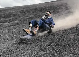  ??  ?? Andrew Goldfarb slides down the face of the Cerro Negro volcano on a sand board.