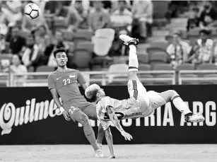  ?? - AFP photo ?? Emmanuel Mammana (R) of Argentina takes a kick against Singapore during the internatio­nal friendly football match between Argentina and Singapore at the National Stadium in Singapore on June 13, 2017.