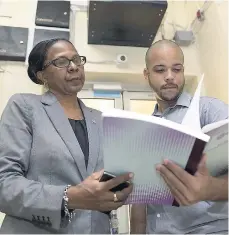  ??  ?? Kathleen Cooper-Brown (left), Kingston Public Hospital administra­tor, and Jason Ennevor, acting operations manager at the hospital, review a logbook in the morgue.