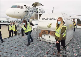  ?? Pool / Getty Images ?? UPS employees move one of two shipping containers containing the first shipments of the Pfizer and BioNTech COVID-19 vaccine at UPS Worldport in Louisville, Ky., on Sunday. The flight originated in Lansing, Mich.